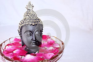 Buddha god face among rose petals