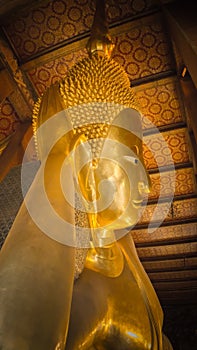 the Buddha gold statue face in the Temple of the Reclining Buddha , Wat Pho, Bangkok, Thailand