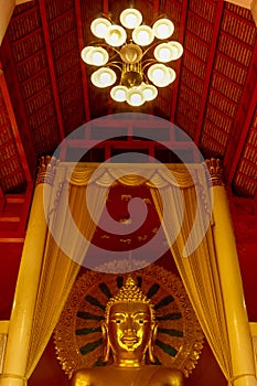 Buddha with golden halo under huge candelabrum