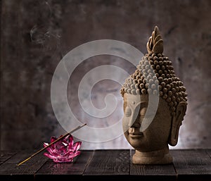 Buddha head statue, incense and lotus flower decoration.
