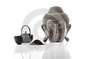 Buddha head, teapot, cup and tea on a white background