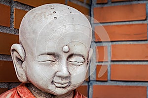 buddha kid sculpture Statue at Japanese temple child, boy, orange red bricks background