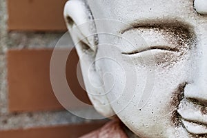 buddha kid sculpture Statue at Japanese temple child, boy, orange red bricks background close up