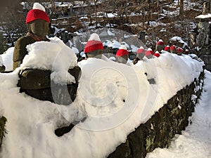 Buddha Narabi Jizo statues with red hats landmark under snow in