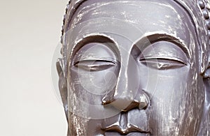 Buddha`s face close-up. The Buddha image in ceramics. The texture of the background and focus of the soft focus.