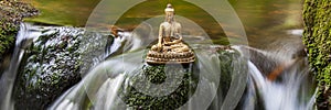 Buddha sculpture sitting in flowing water cascade