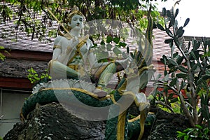 Buddha sitting on a green dragon statue.