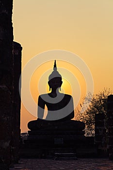 Buddha statue against sunset silhouette, Wat Maha That