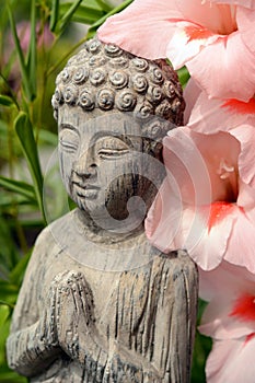 Buddha statue in a flowergarden with pink flowers