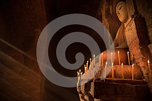 Buddha statue inside the pagoda with candle light under the ray of light