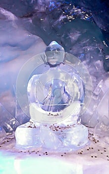 A buddha statue made of ice covered in coins for good luck inside ofa glacier grotto