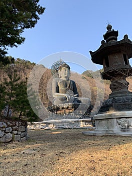 The Buddha statue is meditated by a mountain in the ground.