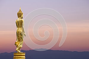 Buddha statue standing on sunset sky background