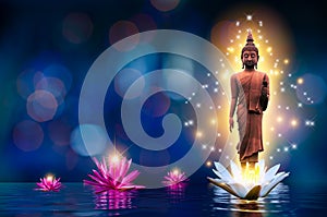 The Buddha statue stands on a white and pink lotus in the water. Bokeh blue background