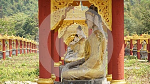 Buddha Statues in a green field at the base of Mount Zwegabin near Hpa-An, Myanmar.