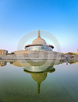 Buddha stupa with water reflection and bright blue sky at morning