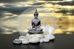 Buddha,zen stone,white orchid flowers and dark sky and clouds reflected in water