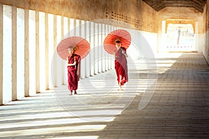 Buddhism novices are walking with umberella in temple