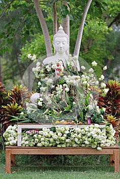 Buddhism worship with offering flowers and garland to buddha statue