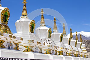 Buddhist chortens, white stupa and Himalayas mountains in the background near Shey Palace in Ladakh, India