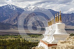 Buddhist chortens, white stupa and Himalayas mountains in the background near Shey Palace in Ladakh, India