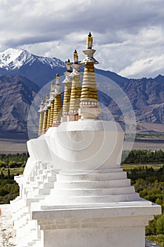 Buddhist chortens, white stupa and Himalayas mountains in the background near Shey Palace in Leh in Ladakh, India