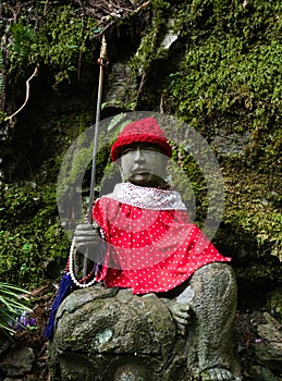 Buddhist Jizo statue in red garments on a mountain path leading to Iwayaji, temple number 45 of Shikoku pilgrimage