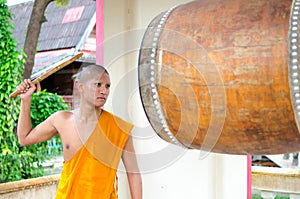 Buddhist monk, hitting the drum in the temple.