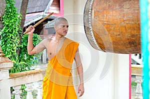 Buddhist monk, hitting the drum in the temple.