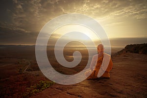 Buddhist monk in meditation at beautiful sunset or sunrise background