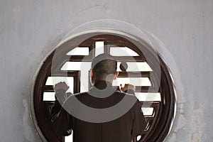 Buddhist monk stands by a round window