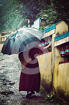 Buddhist monk with umbrella spinning prayer wheels photo