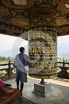 Buddhist pilgrim praying with a prayer wheel in Chimi Lhakang Monastery, Bhutan