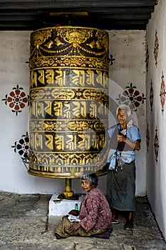 Buddhist pilgrim praying with a prayer wheel in Chimi Lhakang Monastery