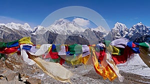 Buddhist prayer flags flying in the wind on the top of Renjo La pass, Himalayas, Nepal with mountain panorama.