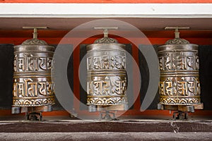 Buddhist prayer wheels in Tibetan monastery with written mantra. Himalayan village, Nepal