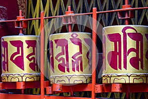 Buddhist prayer wheels in Tibetan monastery with written mantra. India, Himalaya, Ladakh, Buddhist prayer drums with close-up mant