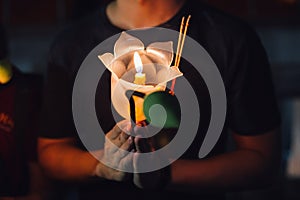 Buddhist praying with incense sticks, lotus flower and candles on holy religion day of Vesak at night.