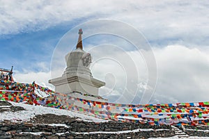 Buddhist Stupa with prayer flags on snow mountain