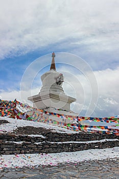 Buddhist Stupa with prayer flags on snow mountain