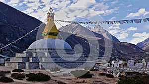 Buddhist stupa in a valley near Thame, Khumbu, Himalayas, Nepal with prayer flags flying in the wind and a wall of mani stones.