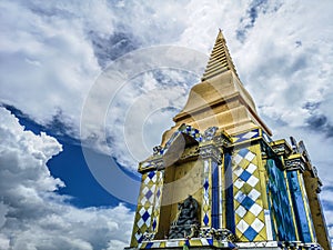 Buddhist temple in clouds, low angle view of golden pagoda with amazing cloudy sky