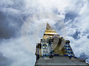 Buddhist temple in clouds, low angle view of golden pagoda with amazing cloudy sky
