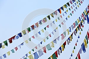 Buddhist tibetan prayer flags waving in the wind against blue sk