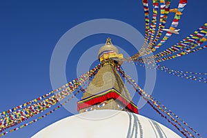 Buddhist Tibetan stupa Bodnath in Kathmandu with multicolored prayer flags against a clean blue sky