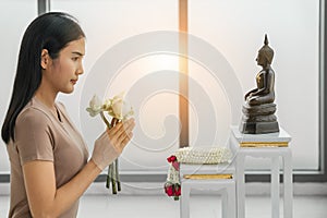 Buddhist woman holding lotus flowers worship to buddha statue at home