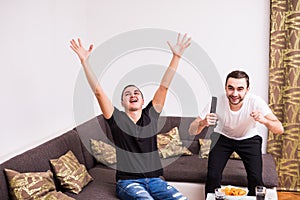 Buddies watching football match on tv at home with victory screams