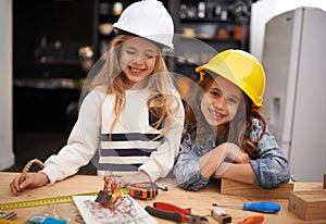 Budding little inventors. two little girls in hard hats playing with tools at home.