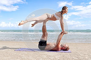 Buddy athlete doing yoga and stretching body on summer beach, couple practicing yoga, man lift woman up at seashore of tropical