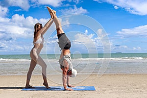 Buddy athlete woman, man do yoga and turns cartwheel on summer island beach, couple practicing yoga at seashore of tropical ocean